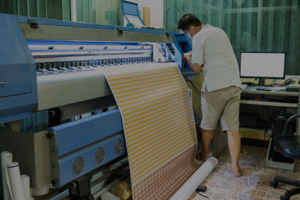 A technician in a print shop operates a large industrial printer, highlighting the capability to produce a wide variety of custom large-format materials and designs.