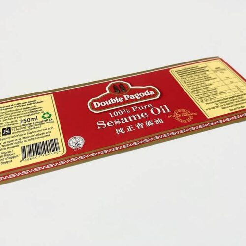 A close-up of a high-quality, custom-printed product label for Double Pagoda Sesame Oil, featuring an elegant red and gold design with foil accents
