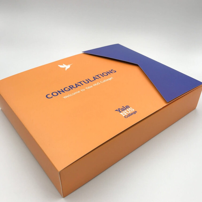 An elegant orange and blue custom presentation box for Yale-NUS College, featuring a unique die-cut flap and a 'Congratulations' welcome message.