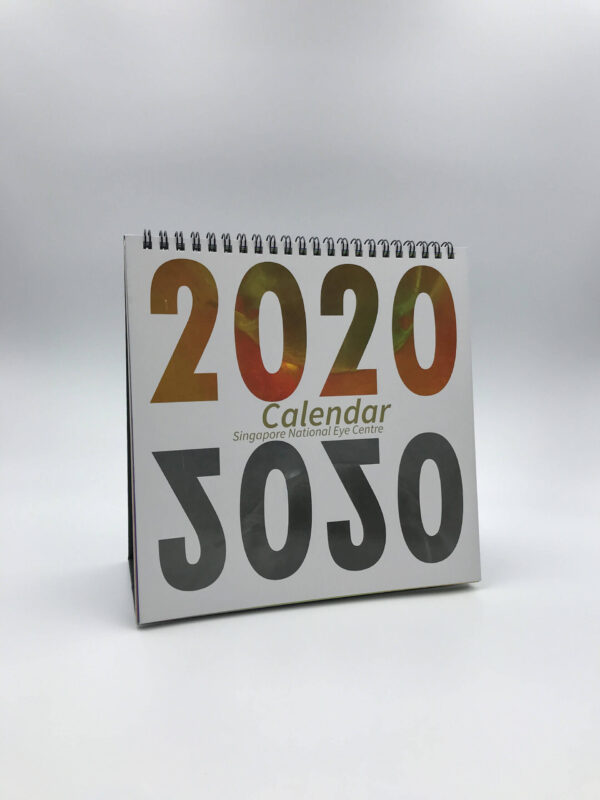 A custom-printed 2020 desk calendar for the Singapore National Eye Centre, featuring a bold design and standing upright with its wire-o binding