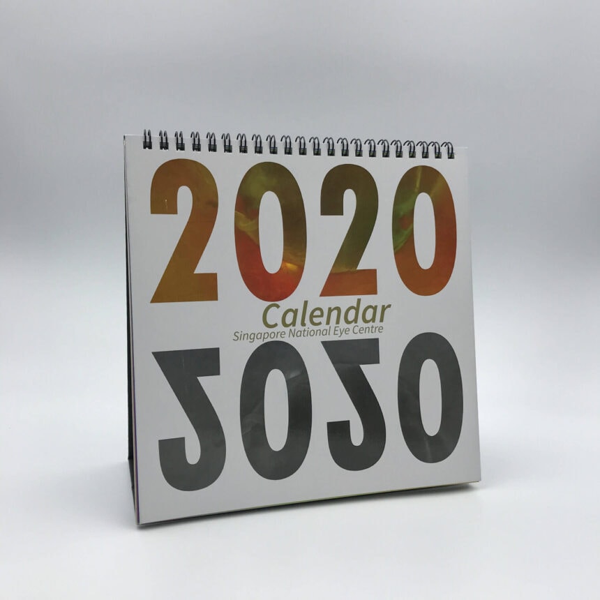 A custom-printed 2020 desk calendar for the Singapore National Eye Centre, featuring a bold design and standing upright with its wire-o binding