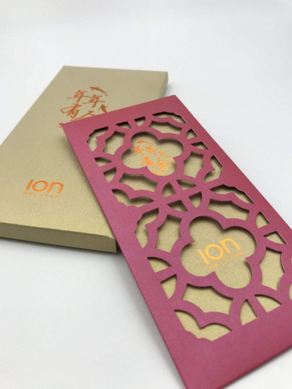 An elegant Chinese New Year red packet from ION Orchard, featuring an intricate laser-cut floral pattern on the sleeve