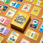 The 'Market Blitz' card game box is displayed on an orange surface, surrounded by a wide array of professionally printed, illustrated playing cards