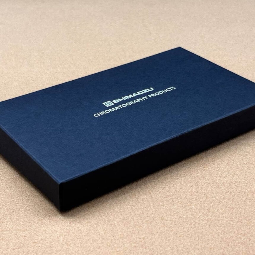 An elegant and minimalist black rigid box for Shimadzu Chromatography Products, featuring a clean design and a silver foil stamped logo on a textured surface.