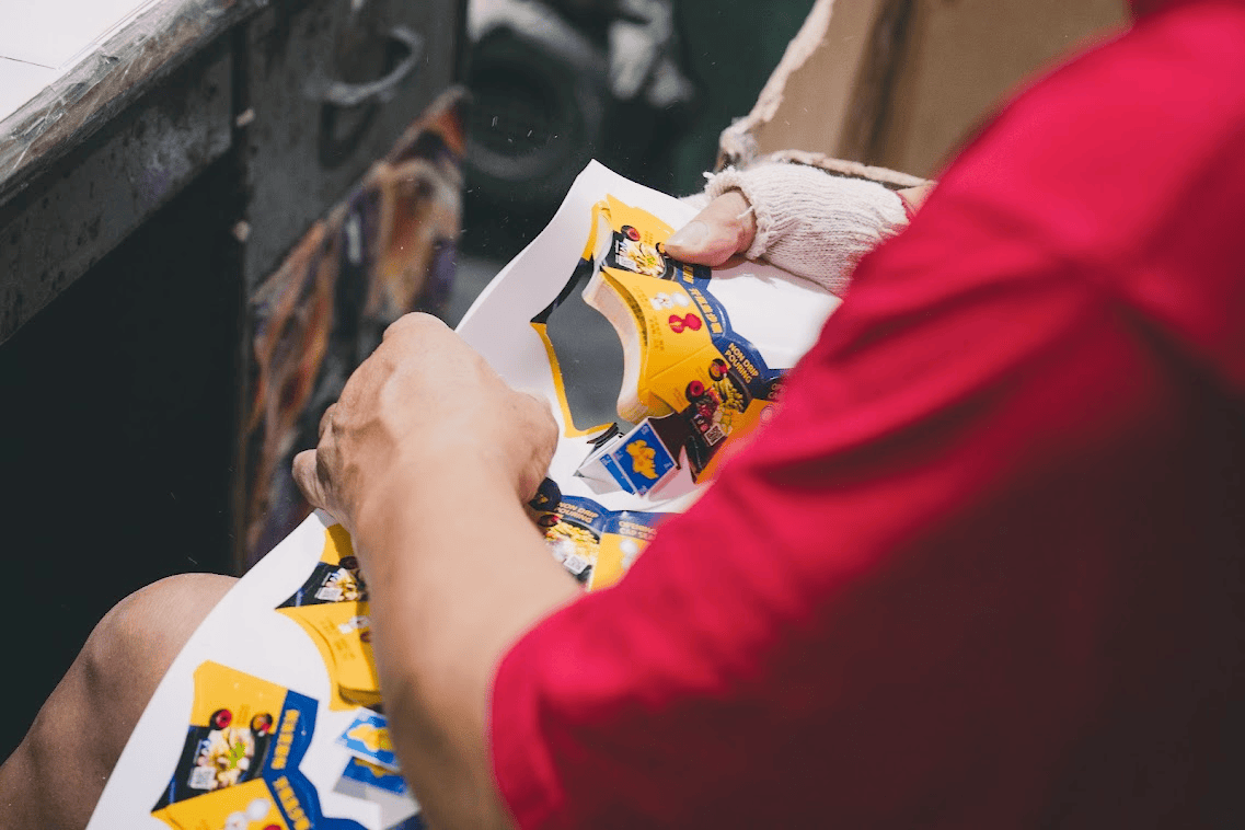 close-up of a worker's hands folding or assembling printed yellow and blue product packaging material.