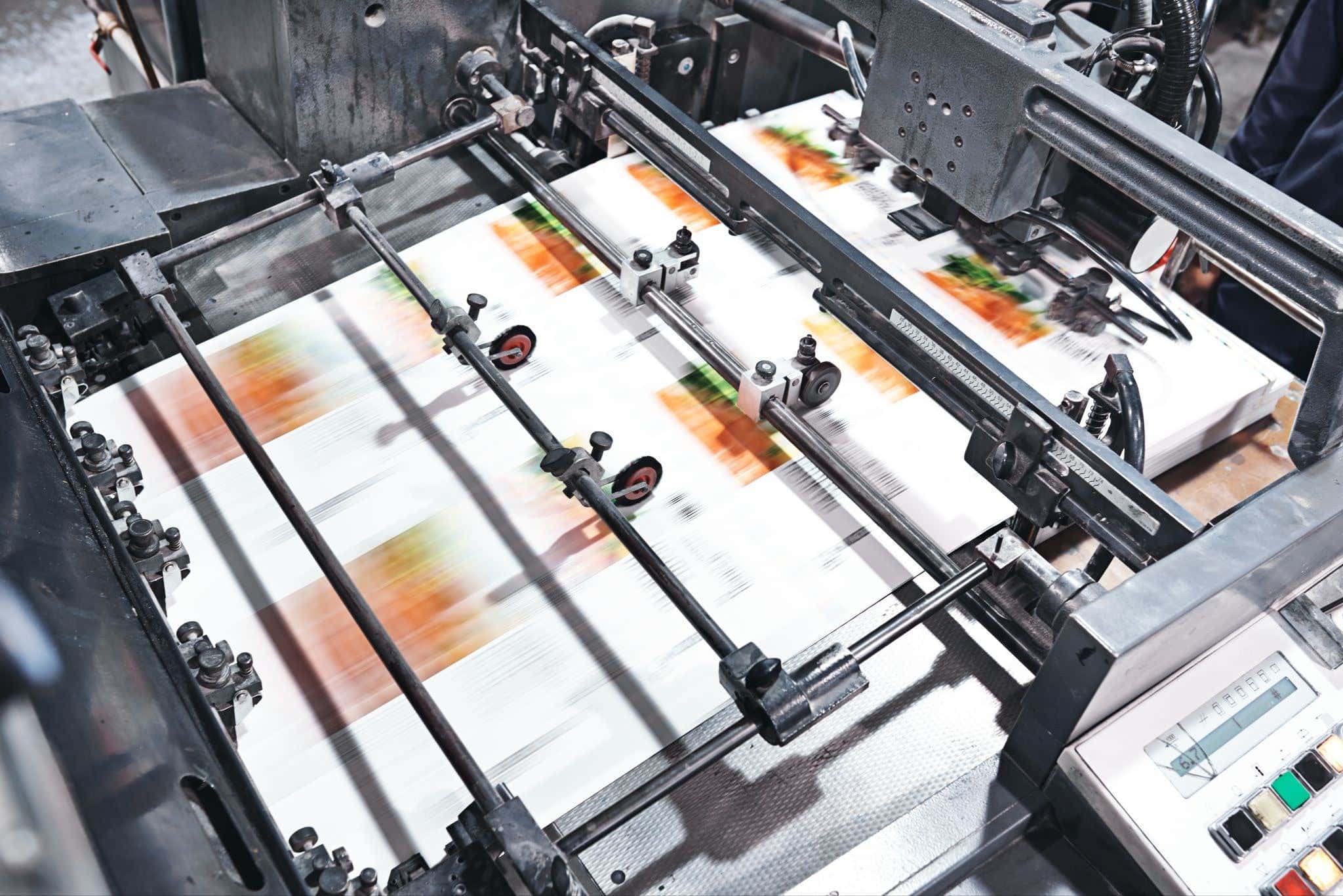 Offset printing press running color sheets, showing types of lamination in printing process.