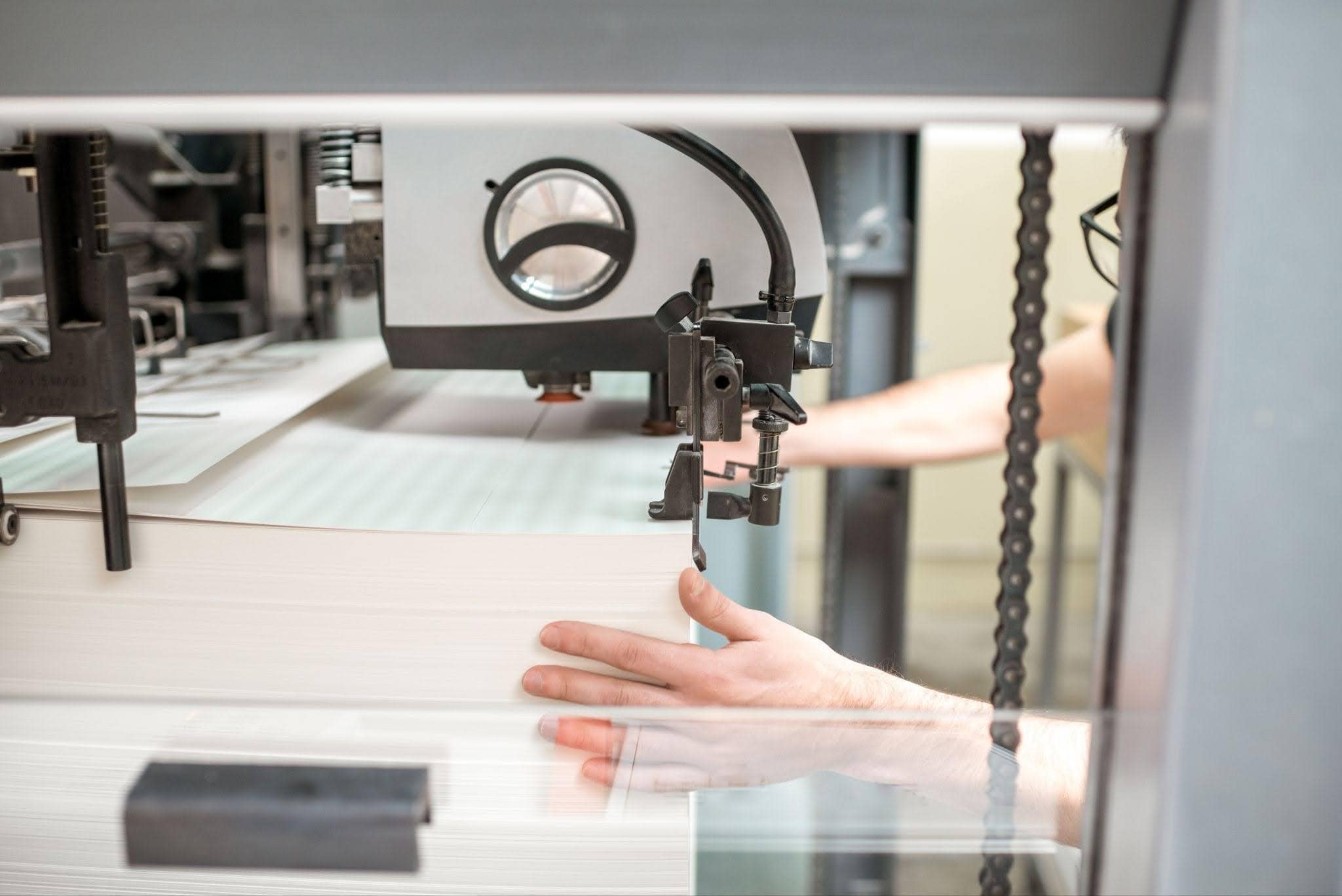 Printing press operator adjusting paper feed, illustrating types of lamination in printing.