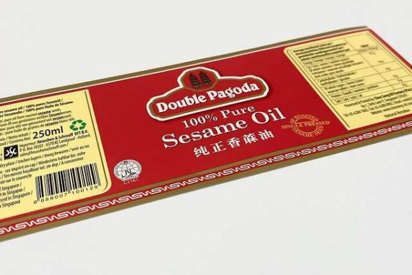 A close-up of a high-quality, custom-printed product label for Double Pagoda Sesame Oil, featuring an elegant red and gold design with foil accents