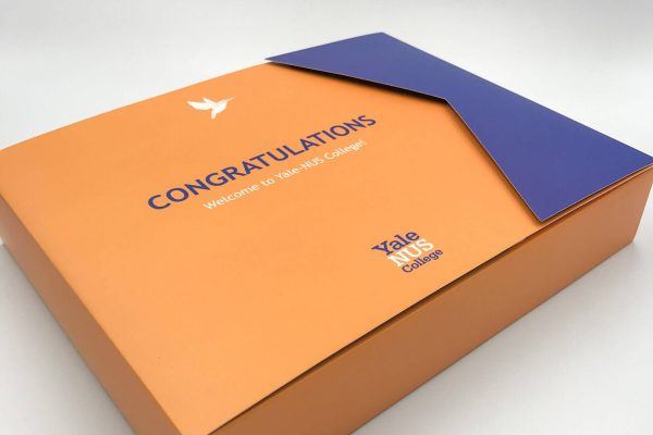 An elegant orange and blue custom presentation box for Yale-NUS College, featuring a unique die-cut flap and a 'Congratulations' welcome message.