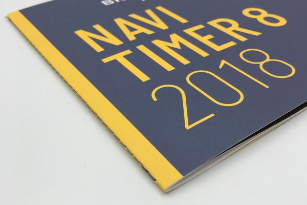 A high-quality, custom-printed product brochure for Breitling watches, with a striking dark blue and yellow cover design for the Navitimer 8 2018 model.