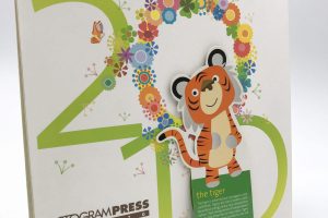 A custom-printed, spiral-binding desk calendar featuring a colorful floral design, a cute tiger illustration, and corporate branding for Octogram Press.
