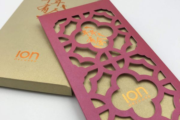 An elegant Chinese New Year red packet from ION Orchard, featuring an intricate laser-cut floral pattern on the sleeve