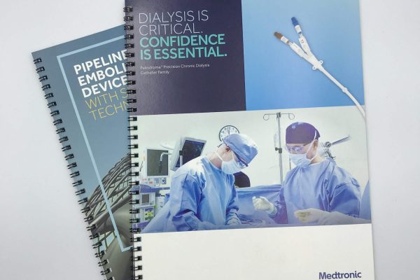Two spiral-bound corporate brochures for Medtronic, a medical technology company, featuring high-quality images of medical procedures and devices on their covers
